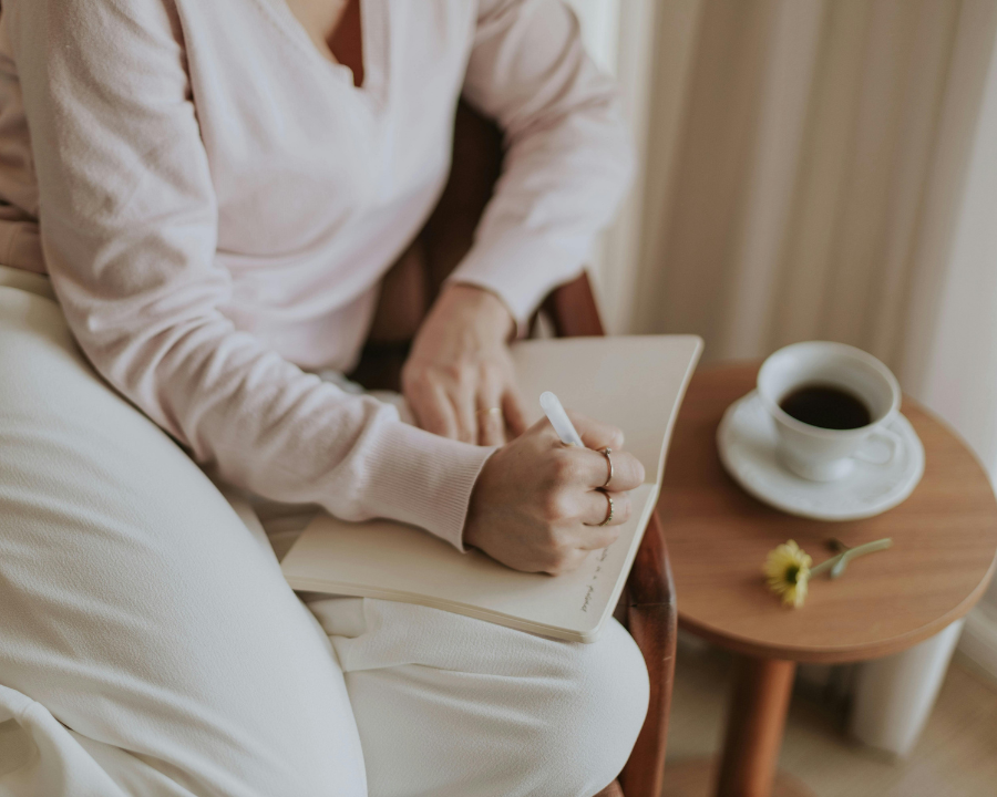 woman writing a journal on a sofa beside a coffee table, quiet reflection sets the stage for genuine mindset shifts and comparison