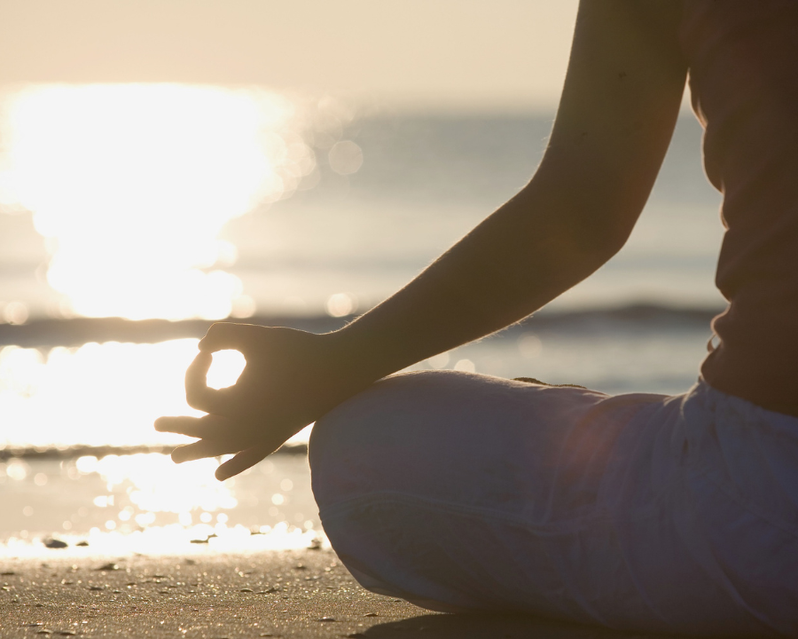 picture of a person meditating on a beach beside a sea