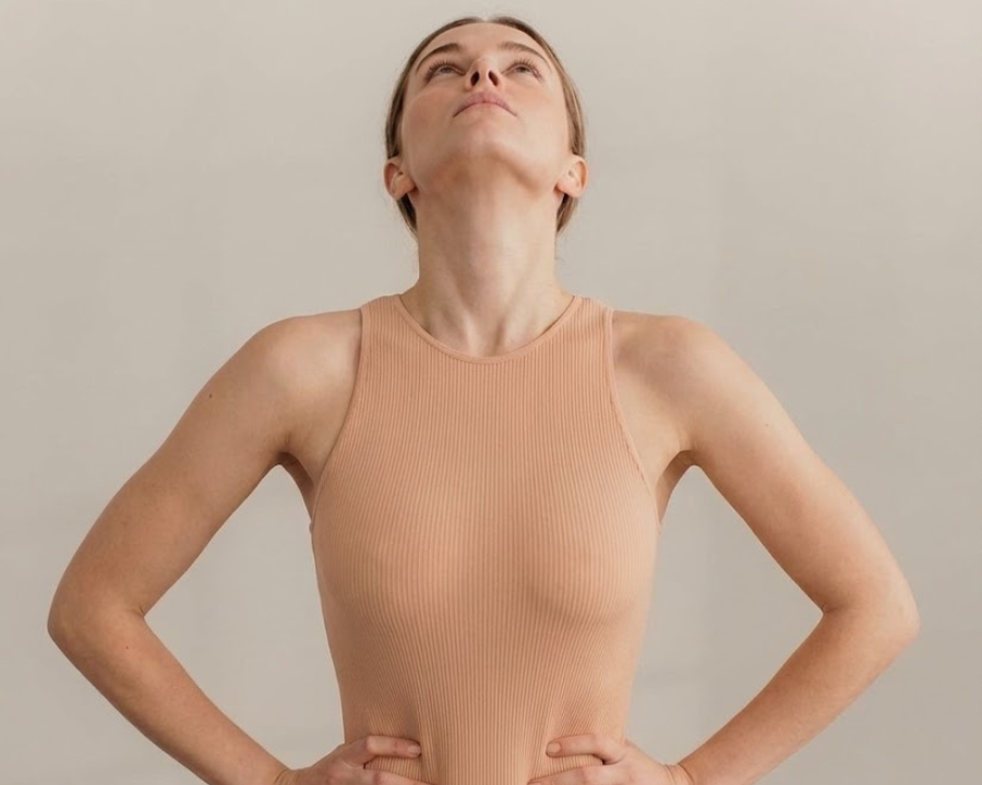 woman standing with her chin up, taking a deep breath with her arms on her waist while becoming emotionally aware